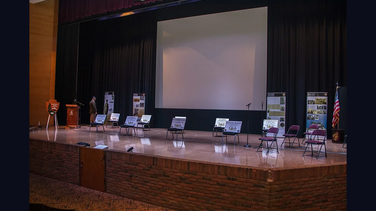 A small event stage with a large screen and chairs